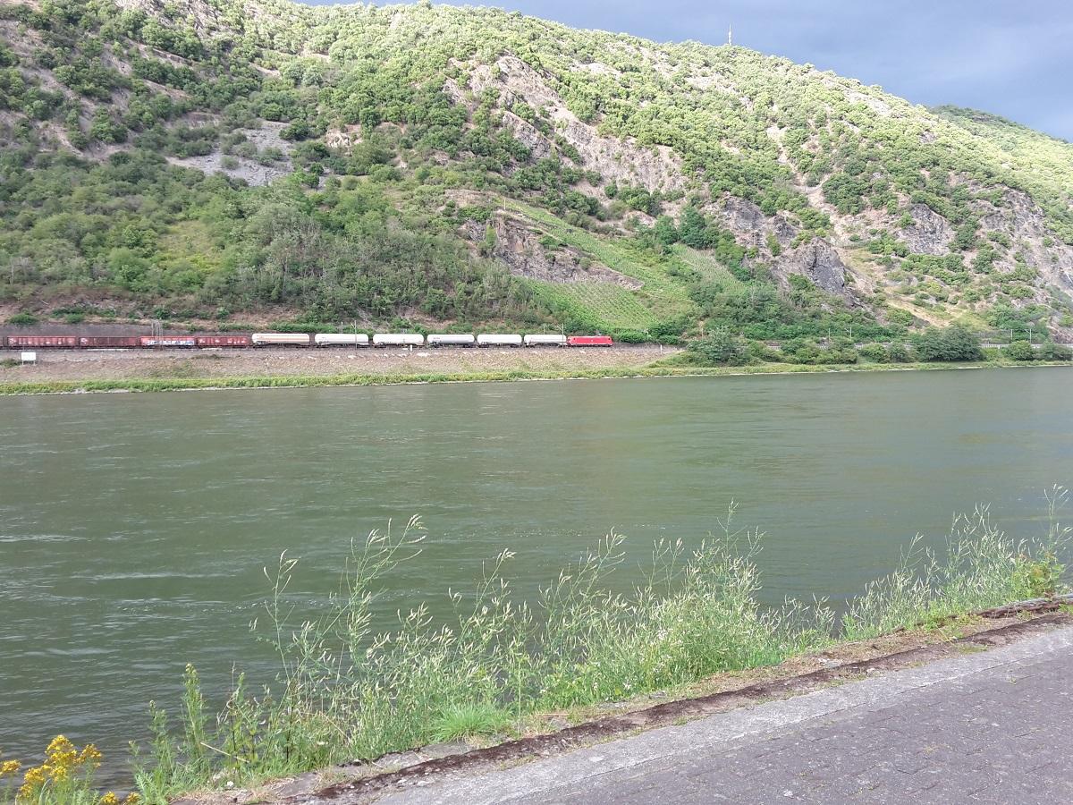 73H ZITTEND OP EEN BANKJE AAN DE OEVER VAN DE RIJN ZIET MEN STROMEND WATER EN AF EN TOE EEN TREIN.jpg